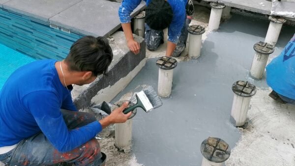 Aplicación de Soudagum Hydro con brocha en superficie junto a piscina como membrana impermeabilizante elástica para evitar filtraciones